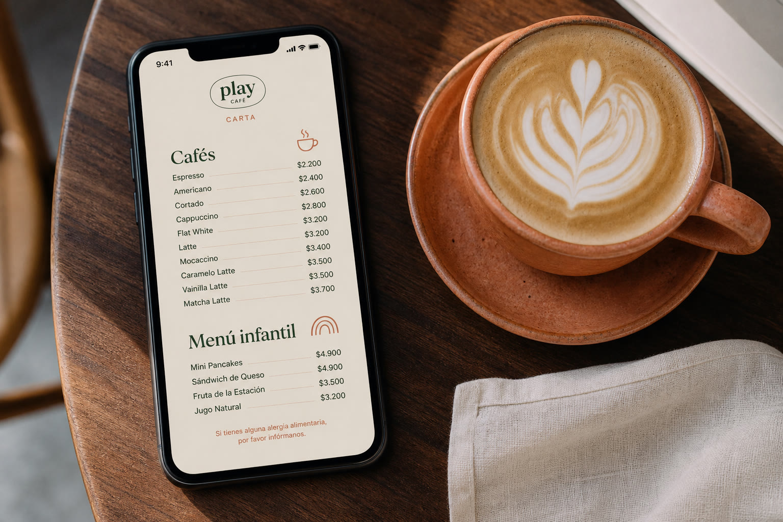 Celular sobre una mesa de café mostrando la carta digital junto a un flat white